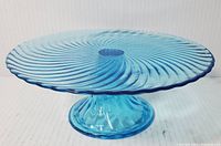 Side view of the turquoise glass cake stand showing the swirl pattern and pedestal base.