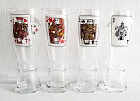 Front view of the four vintage beer glasses showing playing card face designs: King of Diamonds, Queen of Hearts, King of Clubs, and Ace of Spades. Clear glass, about 8.5 inches tall with flared bases.