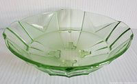 Angled view of the green footed glass bowl showing its octagonal shape, facets, and four footed support on base.