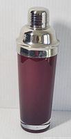 Front view of ruby red glass cocktail shaker with metal cap against white background