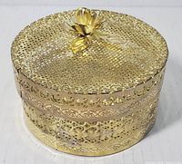 Top-front angle showing the gold-tone filigree box with raised flower on the lid