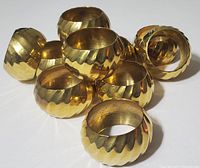 Group view of ten solid brass napkin rings showing their rounded scalloped design and polished finish, some light surface wear visible.