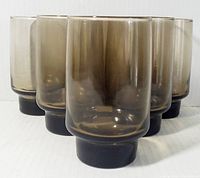 Six 1970's Libbey smokey brown beverage glasses arranged in a triangular formation showing front and side views, highlighting color and thick base.