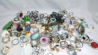 Top-down view of the assortment of colorful and uniquely designed fantasy rings spread out on a white surface.
