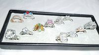 Top view showing all 12 rings in a black tray on white background
