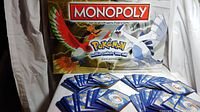 Pokemon Monopoly Johto Edition game box with artwork of Ho-Oh and Lugia, cards spread out beneath