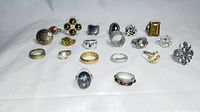 Photo of 20 assorted vintage costume rings of mixed metals showing varying sizes, stone types including faux pearls, red stones, clear crystals, black stones, and amber rectangular stone highlights.