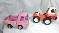 Pink Kitty Kennel toy truck (pink color) and red tractor trailer hauler cab (red and white) placed side by side showing front and side views
