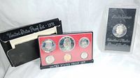Two proof sets displayed, one with red backing holding five bicentennial coins, and a separate clear case containing an Eisenhower bicentennial silver dollar.