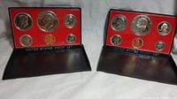 Two United States Mint proof coin sets from 1976 with red interior backing cases and six coins each.