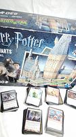 Box of Harry Potter 3D Wrebbit Hogwarts Great Hall puzzle showing box front and part of puzzle pieces. Several Magic The Gathering cards are spread in front of the box.