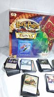 Photo of Harry Potter Chamber of Secrets Trivia game box with stacks of Magic The Gathering cards to the front and right.
