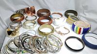 Wide view showing a collection of mixed material bangles and bracelets including metal, wood, plastic, and beaded pieces in various sizes and shapes.