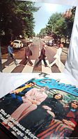 Photo showing the Beatles Abbey Road vinyl record sleeve with the band crossing the street and the book titled 'The Fabulous Story of John, Paul, George and Ringo' partially visible in front.