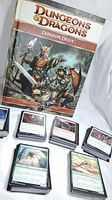 Photo showing the Dungeons & Dragons Dungeon Delve role-playing game supplement book with stacks of Magic: The Gathering cards assembled in front.