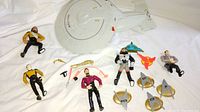 Wide shot of the entire Star Trek toy collection showing USS Enterprise NCC-1701-D and character figures arranged on a white sheet.