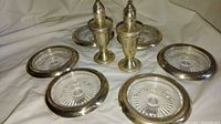 Six crystal ashtrays with sterling silver rims along with a pair of sterling silver weighted salt and pepper shakers arranged on a white cloth.