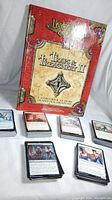 Front view of Legends of Cthulhu Traps & Treachery II sourcebook with multiple stacks of Magic The Gathering cards laid out in front.