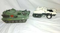 Green 1986 Lanard GI Joe tank and white 1985 Hasbro Snow Cat vehicle shown side by side on white background.