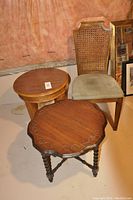 Chair with cane back and upholstered seat beside two wooden side tables with round tops