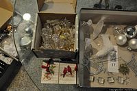 Various miscellaneous silver and glass Christmas decorations arranged on a table, including glass ornaments and metal decorations.
