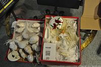 Two open boxes displaying white Christmas bird ornaments and angel-themed Christmas decorations including a red cardinal decoration.
