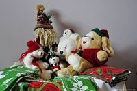 Five Christmas plush toys displayed on and around folded Christmas-themed round tablecloths.