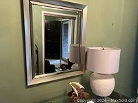 Mirror, lamp, and dolphin sculpture on glass table in foyer.