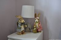 Top and side views of white nightstand with lamp and two Easter bunny decorations on top, showing detail and arrangement.