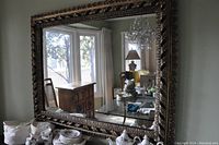 Full frontal view of the rectangular mirror mounted on a wall above a surface with porcelain tea set