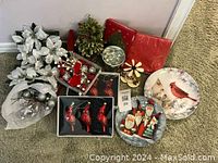 Shows entire lot including poinsettias, candles, Christmas tree, glass ornaments, bird-shaped ornaments, decorative plates, wooden decoration, red gift wrap, and silver bucket.