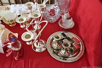 View of set showing two candelabras, two small candle holders on a round tray, glass dish with metal top, and small silver rectangular boxes.