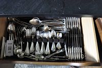 Drawer view of assorted stainless steel cutlery pieces with ornate floral handles: dinner forks, salad forks, teaspoons, tablespoons, serving spoons, carving forks, ladles