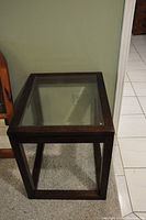 Front view of square side table showing dark wood frame with inset clear glass top