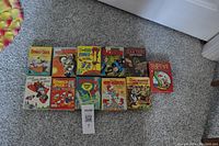 Photo showing 10 vintage comic books featuring classic cartoon and superhero characters arranged on carpet.