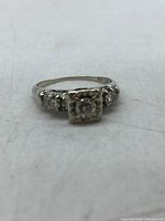 Front view of ring showing square cluster setting with central diamond and shoulder stones