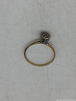 Top view of thin yellow gold ring with cluster of round diamonds in white gold prong setting on top.