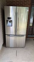 Front view of the Samsung stainless steel refrigerator with water dispenser and three doors.