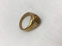 Side angle photo of the vintage gold tone ring with an oval brown stone cabochon and triangular accent with a small clear stone.