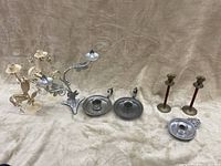 Full lot showing three pairs of candle holders plus two individual holders on a beige fabric background.