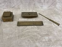 Photo showing the four items laid out flat on cloth background: inkwell, blotter, letter opener, and tray, highlighting overall condition and patina.