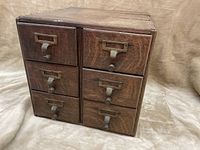 Front view of antique wooden card catalogue with 9 drawers in weathered oak finish.