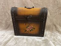 Front view of antique wooden case showing the ribbed curved top, woven edge detailing, floral painting on front panel, and metal latch.