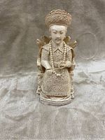 Front view of Chinese empress figurine showing detailed carved face, clothing, and accessories taught to be made from ivory or a similar material.