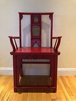 Front view of the Chinese imperial red wooden chair with gold patterned panels on the backrest.