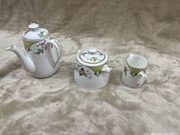 Photo showing the set of three English porcelain tea items: teapot, covered sugar bowl, and creamer with floral and gold detailing
