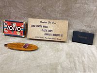 Photo of four vintage games including Lotto game box on left, Roulette set box center with label, Dominoes box on right, and wooden cribbage board with pegs at bottom