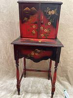 Front view of the red Japanese cupboard showing the two doors and floral landscape painting