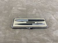 Closed plastic case showing the fountain pen and mechanical pencil set inside with Sheaffer's nameplate.