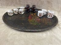 Overview of all items: large oval vintage platter with patina and Asian figure painting, 4 small floral Asian tea cups, 2 small white tea cups with figures, and 2 bear-shaped salt and pepper shakers.